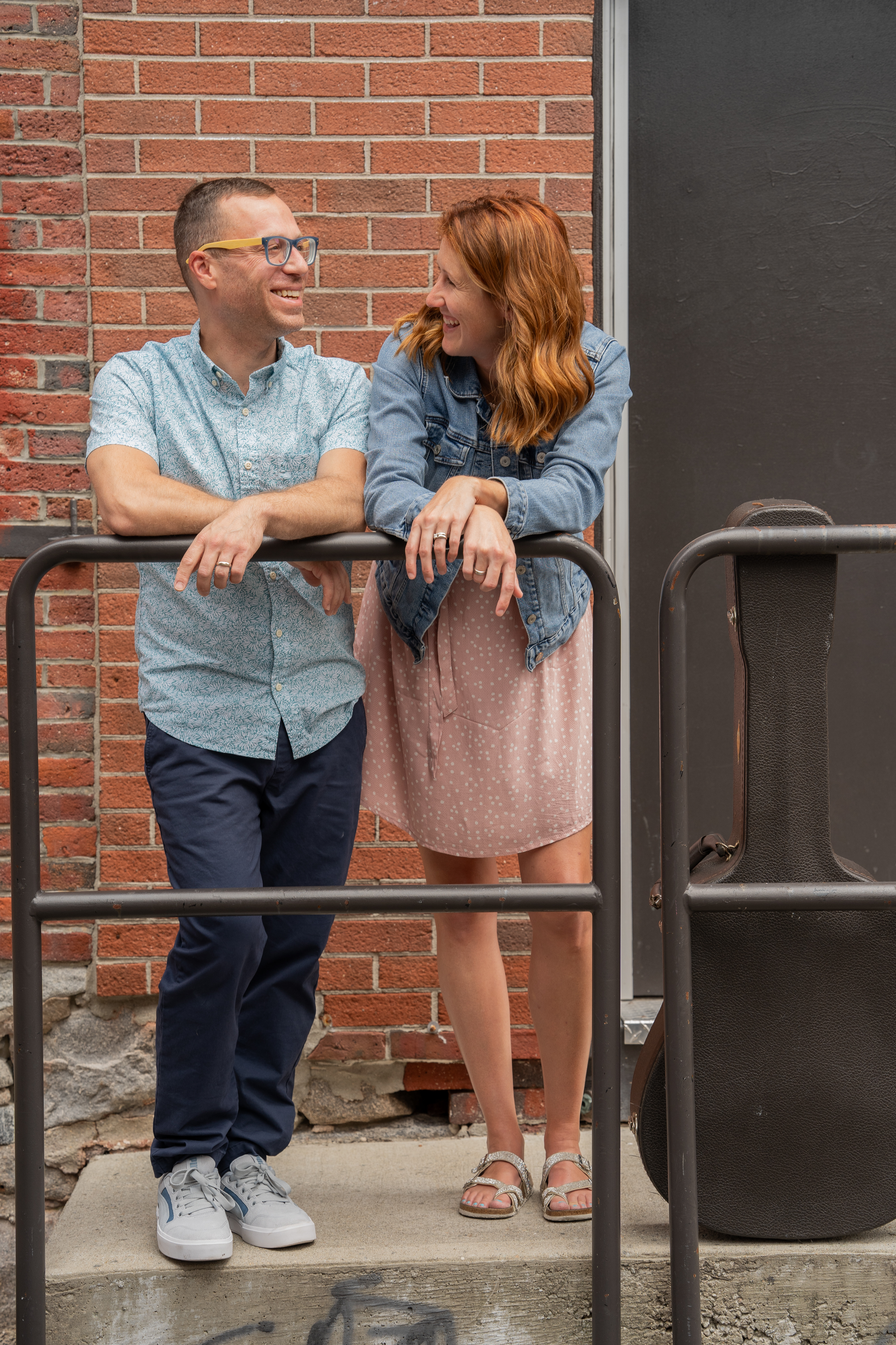 Gus & Jean standing next to a guitar case, smiling and laughing. 